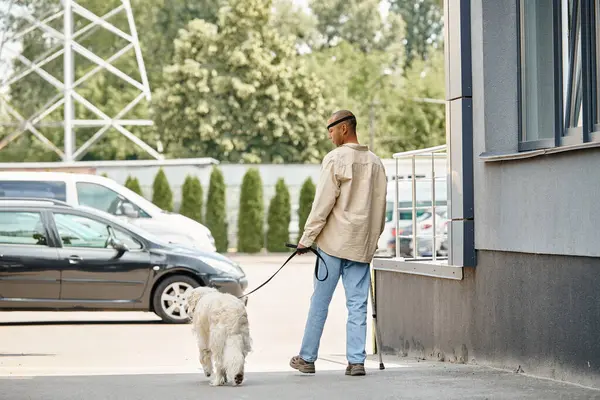 Un afroamericano discapacitado con miastenia gravis pasea con correa a su perro labrador, mostrando diversidad e inclusión. - foto de stock