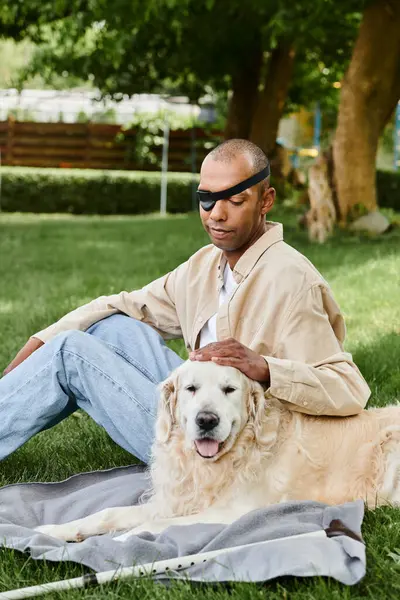 Un hombre afroamericano con síndrome de miastenia gravis se sienta en la hierba con su leal perro Labrador, abrazando la naturaleza y la compañía de los demás. - foto de stock
