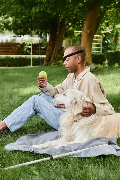 Афроамериканец с синдромом миастении и грависа сидит на траве со своей верной собакой-лабрадором. — стоковое фото
