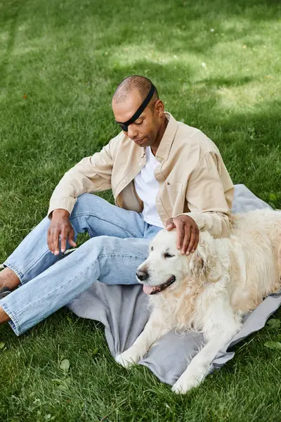 Африканський американець з синдромом міастенії гравіс сидить зі своїм собакою Лабрадором у пишному зеленому трав'яному полі, втілюючи включення. — стокове фото