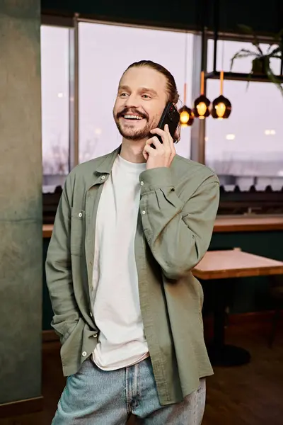 Um homem de pé em um restaurante da moda, envolvido em uma animada conversa telefônica. — Fotografia de Stock