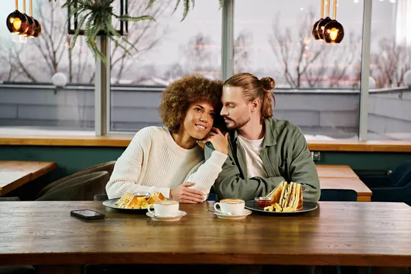 An African American woman and a man enjoying a meal together at a table in a modern cafe. — Stock Photo