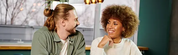 Uma mulher afro-americana e um homem sentados um ao lado do outro em um café moderno, envolvidos em conversa e tomando café. — Fotografia de Stock