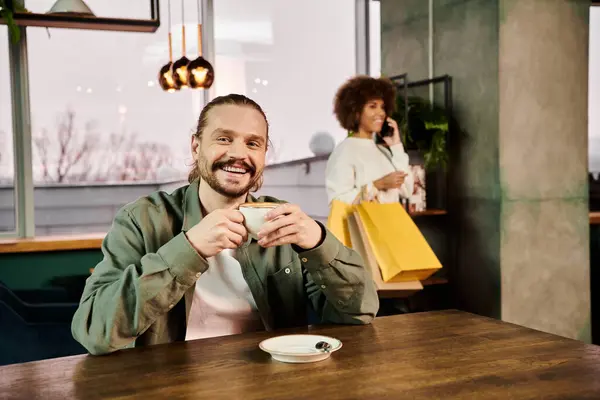 Homme assis à une table, profondément dans la pensée, tenant une tasse de café dans un café moderne confortable. — Photo de stock