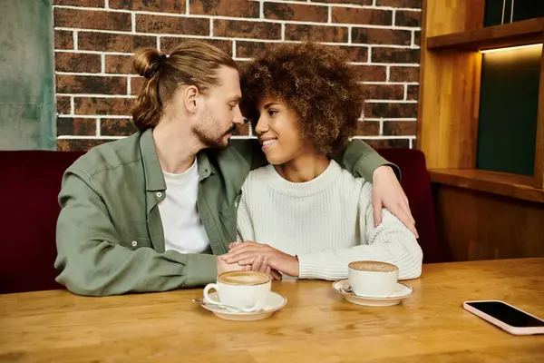 Un uomo e una donna, entrambi afroamericani, seduti a un tavolo da caffè a gustare tazze di caffè insieme. — Foto stock