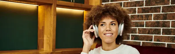 An African American woman wearing headphones in a modern cafe. — Stock Photo