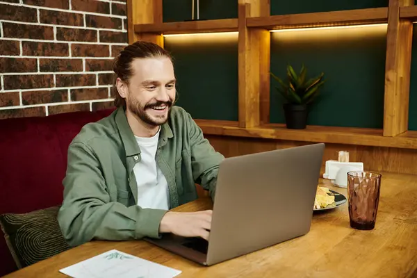 Чоловік інтенсивно зосереджений, використовує ноутбук за столом в сучасному кафе. — стокове фото