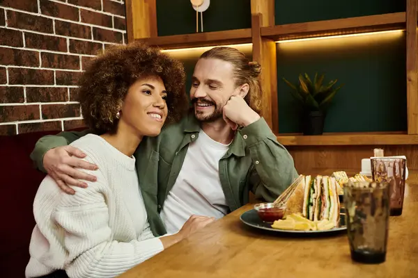 Ein Mann und eine Frau afroamerikanischer Abstammung sitzen an einem Tisch in einem modernen Café und unterhalten sich.. — Stockfoto