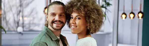 Una mujer afroamericana y un hombre se paran lado a lado en un café moderno, comprometidos en la conversación y la conexión. - foto de stock