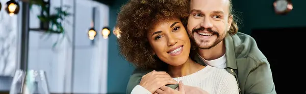 A man tenderly holds a woman in his arms, their connection palpable amidst the modern cafe ambiance. — Stock Photo