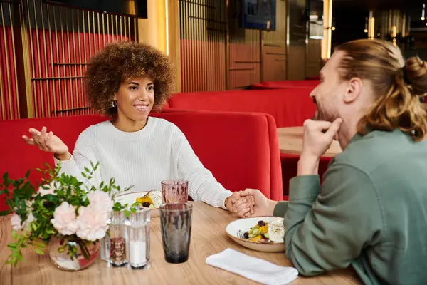 Couple engage in animated conversation at a table in a modern cafe. — Stock Photo
