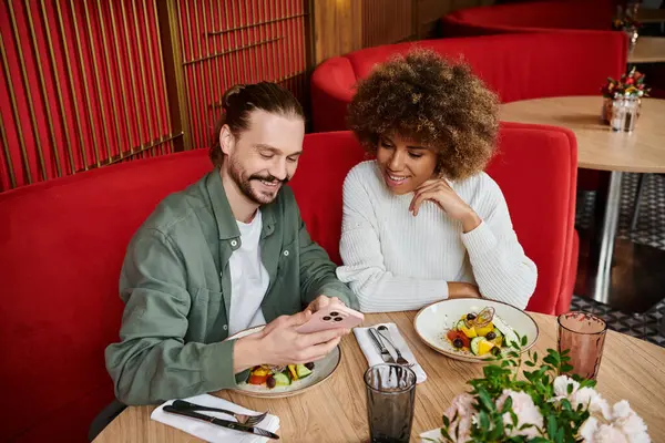 An African American woman and a man engaging in lively conversation at a stylish cafe table. — Stock Photo