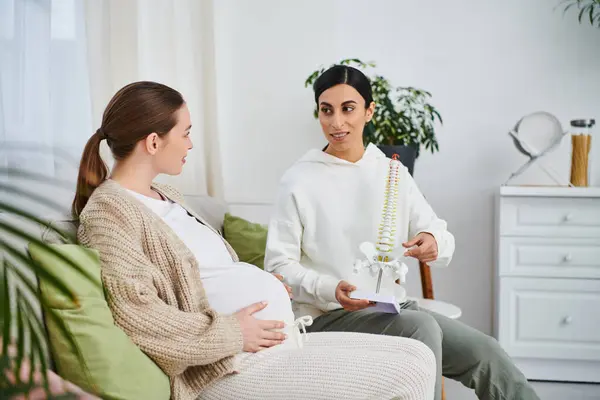 A pregnant woman sitting on a couch next to her trainer during parents courses. — Stock Photo