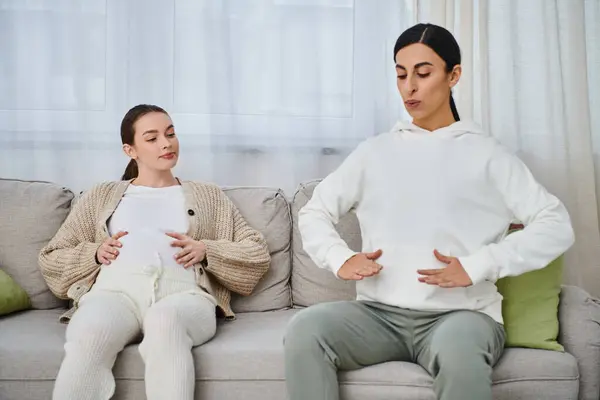 A pregnant woman and her trainer sit atop a couch during a parents course, engaged in conversation. — Stock Photo