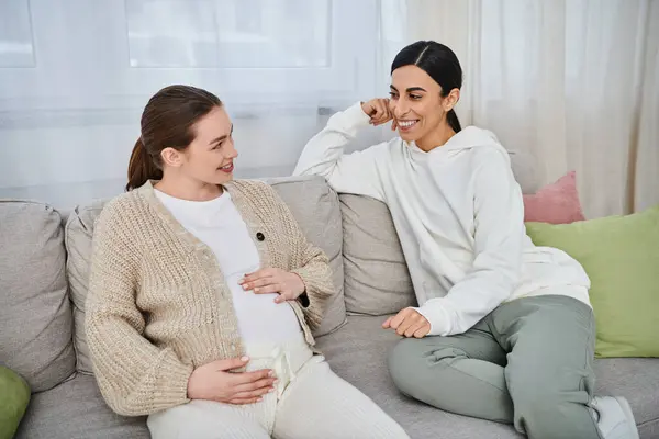 Dos mujeres, una mujer embarazada y su entrenador, participan en una conversación significativa en un sofá durante los cursos de los padres. - foto de stock