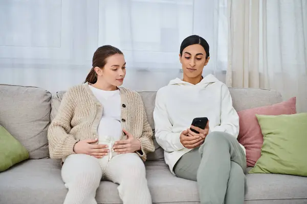 A pregnant woman and her trainer sit comfortably on top of a couch during parents courses. — Stock Photo