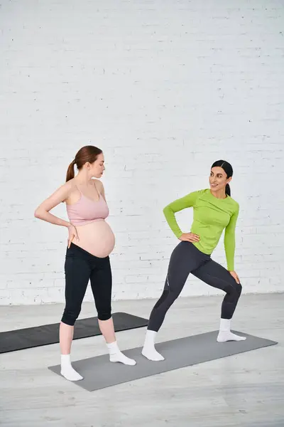 Two pregnant women standing side by side, one coaching the other during a parents course, both displaying strength and unity. — Stock Photo