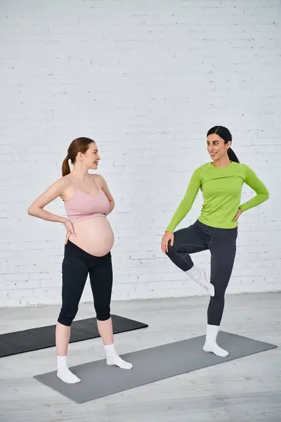 Mujer embarazada en pose de yoga se une al entrenador durante los cursos de padres para el entrenamiento de maternidad dual. - foto de stock