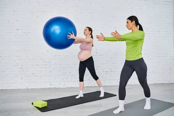 Una mujer embarazada y su entrenador haciendo ejercicios con una pelota durante los cursos de los padres. - foto de stock