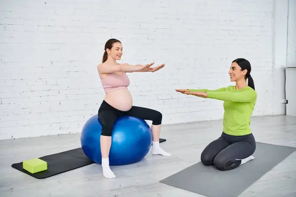 Mujer embarazada, guiada por su entrenador, realizar ejercicios en bolas de ejercicio durante una sesión de acondicionamiento físico prenatal. - foto de stock