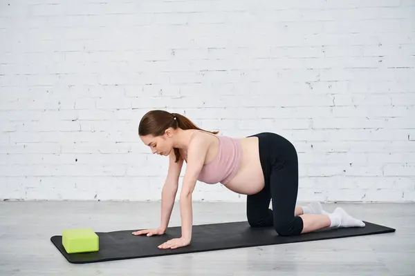 Una donna incinta si impegna in un esercizio di plancia mentre viene guidata dal suo allenatore durante i corsi dei genitori. — Foto stock