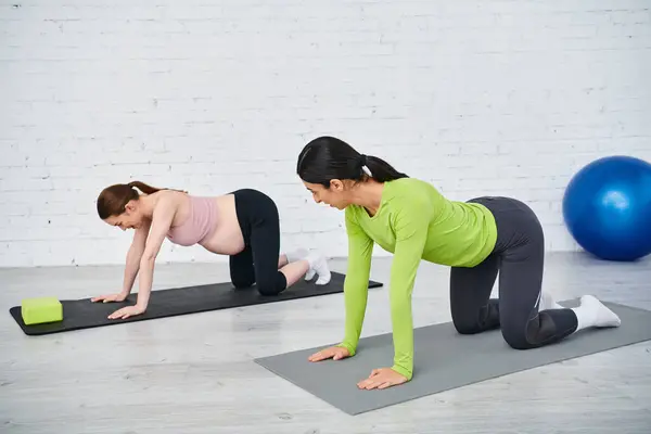 A pregnant woman and her coach performing push ups on yoga mats during a parents course session. — Stock Photo