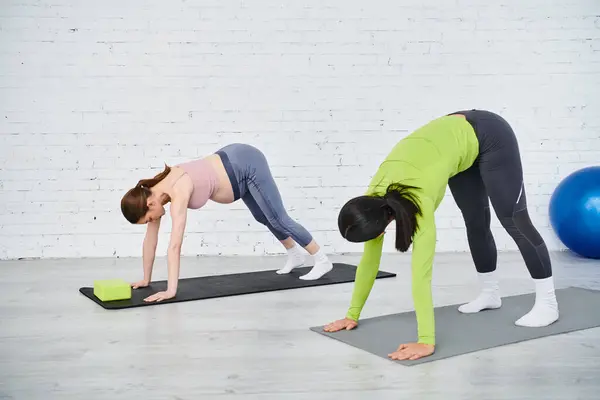 Zwei Frauen praktizieren anmutig Yoga auf Matten in einem ruhigen Raum, wobei sie sich auf ihre Posen und Atmung konzentrieren. — Stockfoto