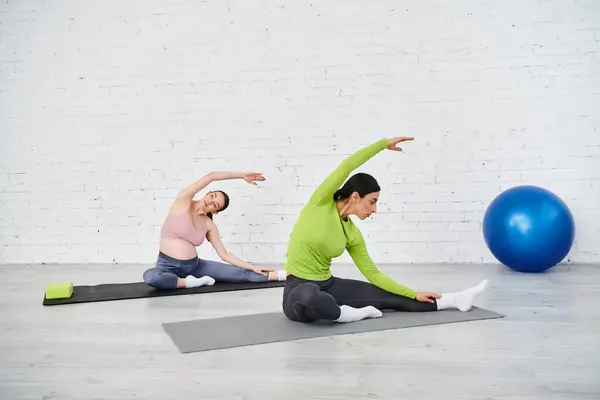 Eine schwangere Frau praktiziert Yoga auf einer Matte, während ihr Ausbilder sie während der Elternkurse führt. — Stockfoto