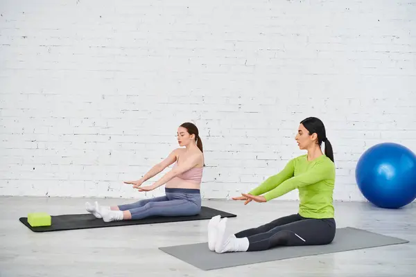 A diverse group of women, including a pregnant woman, are practicing yoga under the guidance of their coach in a serene setting. — Stock Photo