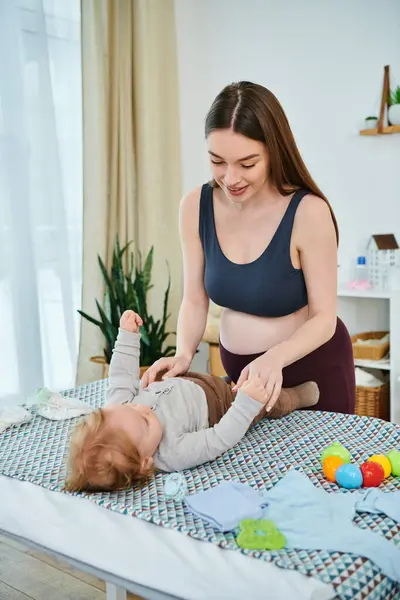 Una madre joven y hermosa interactúa juguetonamente con su bebé en una cama acogedora, cursos para padres. - foto de stock