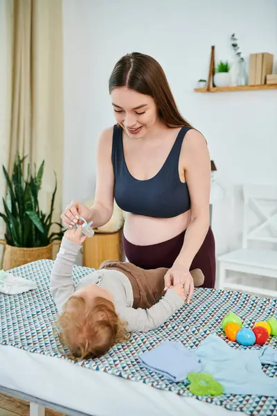Une jeune et belle mère interagit avec son bébé sur une table, cours de parents. — Photo de stock