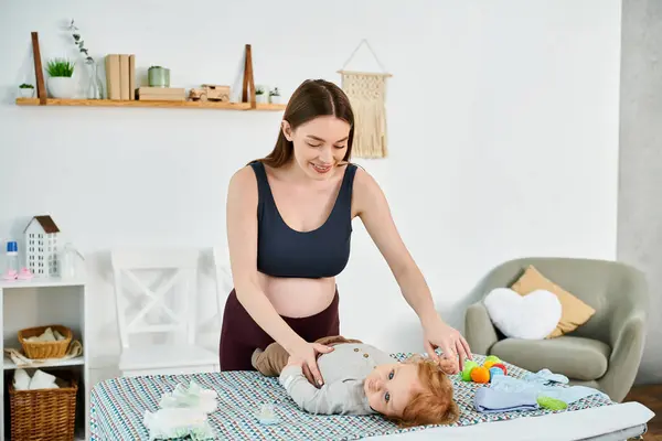 Una madre joven juega alegremente con su bebé en una cama acogedora, guiada por un entrenador experimentado de un curso de padres. - foto de stock