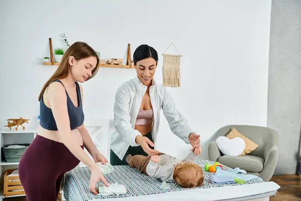 Una giovane bella madre si trova accanto al suo bambino su un letto, ricevendo una guida da un allenatore ai corsi dei genitori.. — Foto stock