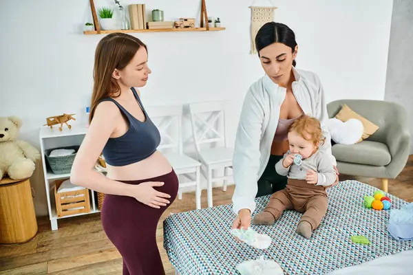 Eine schöne junge Mutter steht neben einem Baby auf einem Bett und lässt sich von ihrem Trainer bei Elternkursen beraten. — Stockfoto