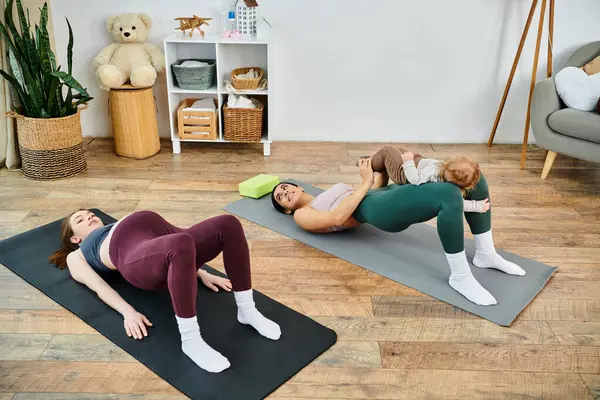 Una madre joven y hermosa y su bebé practicando yoga en casa con la guía de un entrenador durante los cursos de padres. - foto de stock