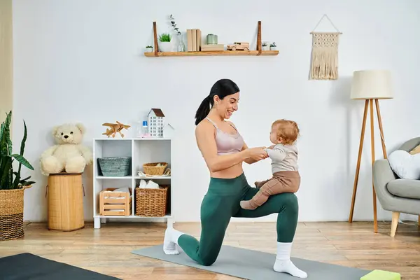 Una joven y hermosa madre practica con gracia yoga con su bebé, guiada por un entrenador en un ambiente hogareño. - foto de stock