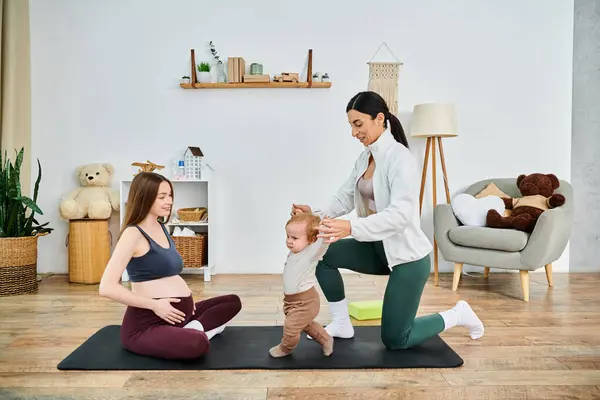 Una joven y hermosa madre practica yoga con su bebé en casa, guiada por su entrenador de cursos para padres. - foto de stock