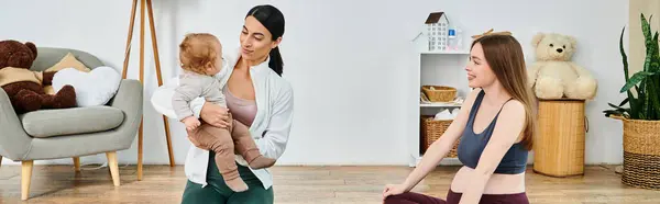 A young, beautiful mother tenderly holds her baby in a warm and inviting living room, guided by her supportive coach from parents courses. — Stock Photo