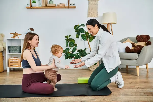 Una giovane bella madre e il suo bambino impegnati in una tranquilla sessione di yoga guidati dal loro istruttore in un corso di genitori. — Foto stock