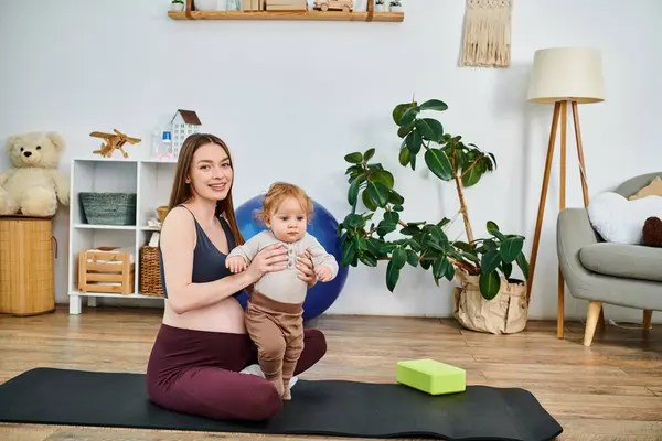 A young mother finds peace on her yoga mat while cradling her baby with the guidance of her coach at parents courses. — Stock Photo