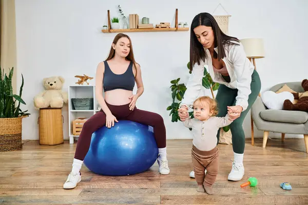 Una madre joven y su bebé jugando felizmente con una pelota, disfrutando de un tiempo de calidad juntos en una sesión de entrenamiento de padres. - foto de stock