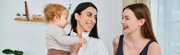 A young, beautiful mother laughs as she holds her baby, receiving guidance from a coach during a parents course at home. — Stock Photo