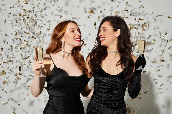 Two elegant women in love, holding wine glasses joyfully. — Stock Photo