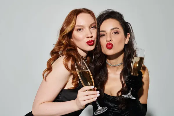 Una coppia lesbica amorevole in abbigliamento elegante, felicemente tenendo bicchieri di vino. — Foto stock