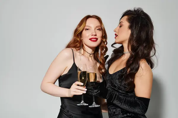 Deux femmes heureuses en robes noires profitant du vin ensemble. — Photo de stock