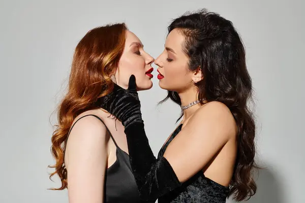 Dos mujeres en traje elegante besándose tiernamente. - foto de stock