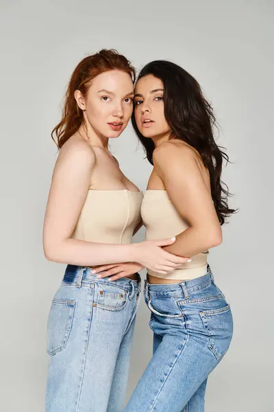 Um casal lésbico amoroso em jeans de cintura alta, posando feliz para a câmera. — Stock Photo