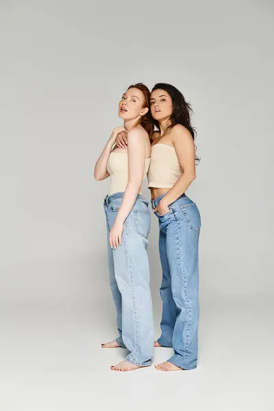 A loving lesbian couple in elegant attire stand side by side in denim jeans, radiating happiness. — Stock Photo