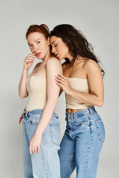 Two women, a loving lesbian couple, standing side by side in jeans, posing happily. - foto de stock