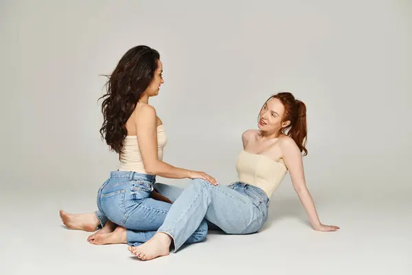 Two elegantly dressed women sit on the ground, engrossed in a deep conversation. — Stock Photo
